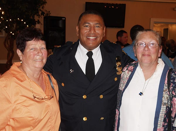 Commander Deon McCaulley welcomes long time Fourth District residents Betty Rodes (on left), and Linda Lewis  (on right) to the ceremony.