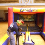 Cleveland Police Officer Vu Nguyen helps one of the children strike the ball on the "Hit A Home Run Game."