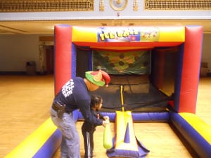 Cleveland Police Officer Vu Nguyen helps one of the children strike the ball on the "Hit A Home Run Game."