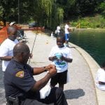 Officer Sam Anderson showing a child the proper way to put a worm on a hook.