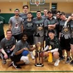 College students in athletic gear pose around a trophy.