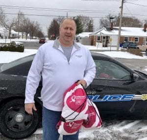 A plainclothes officer steps out of a car holding bags of donated hygenic items.