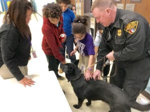 A child pets a police dog at a school.