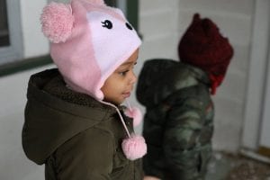 A child wearing a hat gazes in wonder at her new living space.