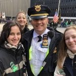 An officer poses outside with three young women.