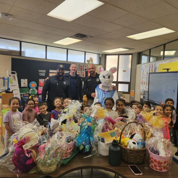 Officers and the Easter Bunny pose with a classroom full of smiling students and donated Easter baskets.