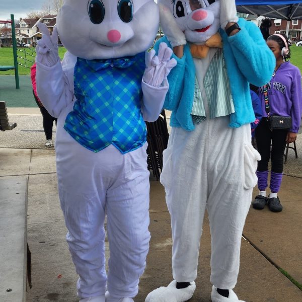 Two people in Easter Bunny costumes pose under a pavilion, making playful gestures toward the camera.