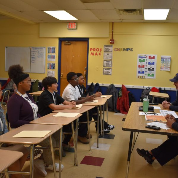Students seated in a classroom across from two Cleveland Police officers, participating in a structured interview session.
