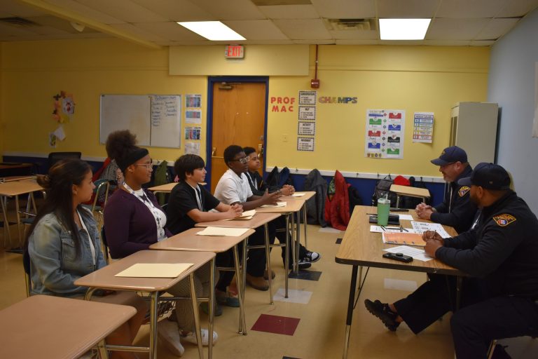 Students seated in a classroom across from two Cleveland Police officers, participating in a structured interview session.