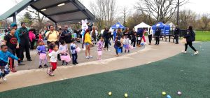 Children race forward with Easter baskets as a crowd of families and volunteers watches during the egg hunt.