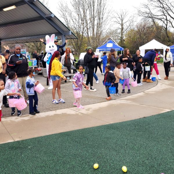 Children race forward with Easter baskets as a crowd of families and volunteers watches during the egg hunt.