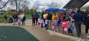 Kids line up along the playground edge holding Easter baskets, waiting for the egg hunt to begin.