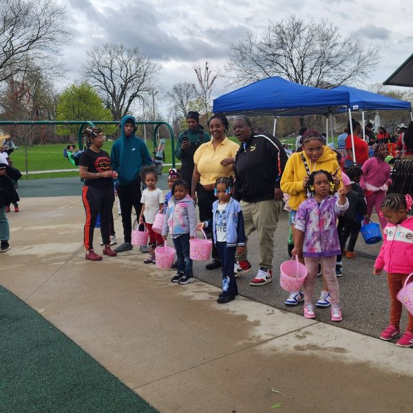 Kids line up along the playground edge holding Easter baskets, waiting for the egg hunt to begin.