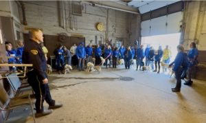 A Mounted Unit officer welcomes a large group of Canine Companions visitors inside the stables.