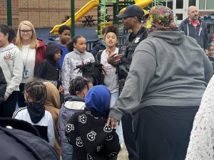 An officer chats with students and staff gathered on the playground during the school cookout.