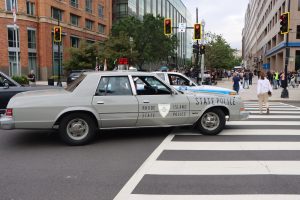 Vintage Rhode Island State Police cruiser crosses an intersection during the NCLEES Memorial March