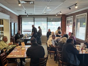 Wide view of My Friends Restaurant during Coffee with a Cop event, with community members and officers gathered at multiple tables