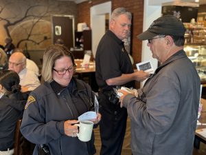 Officer chats with resident holding a mug near front of restaurant