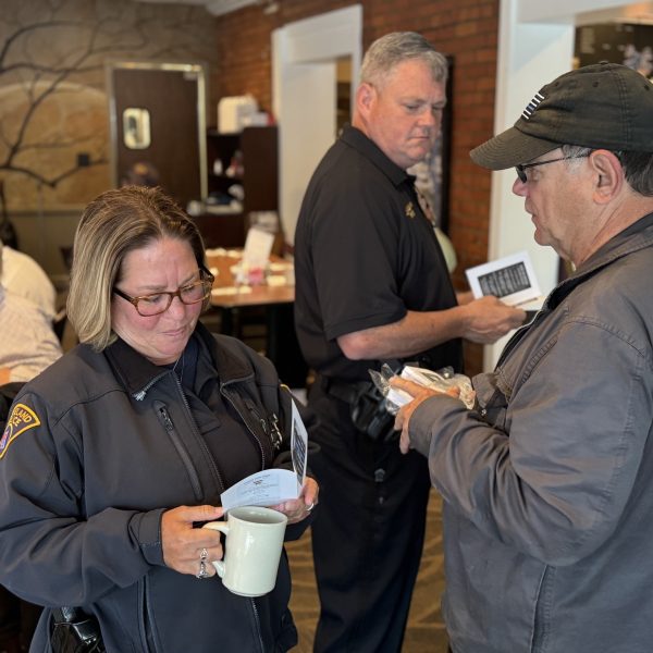 Officer chats with resident holding a mug near front of restaurant