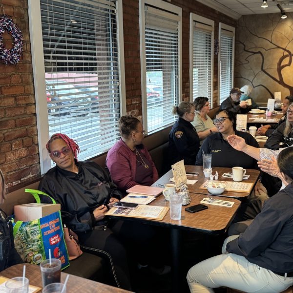 Group photo of officers and residents seated at a long table during Coffee with a Cop