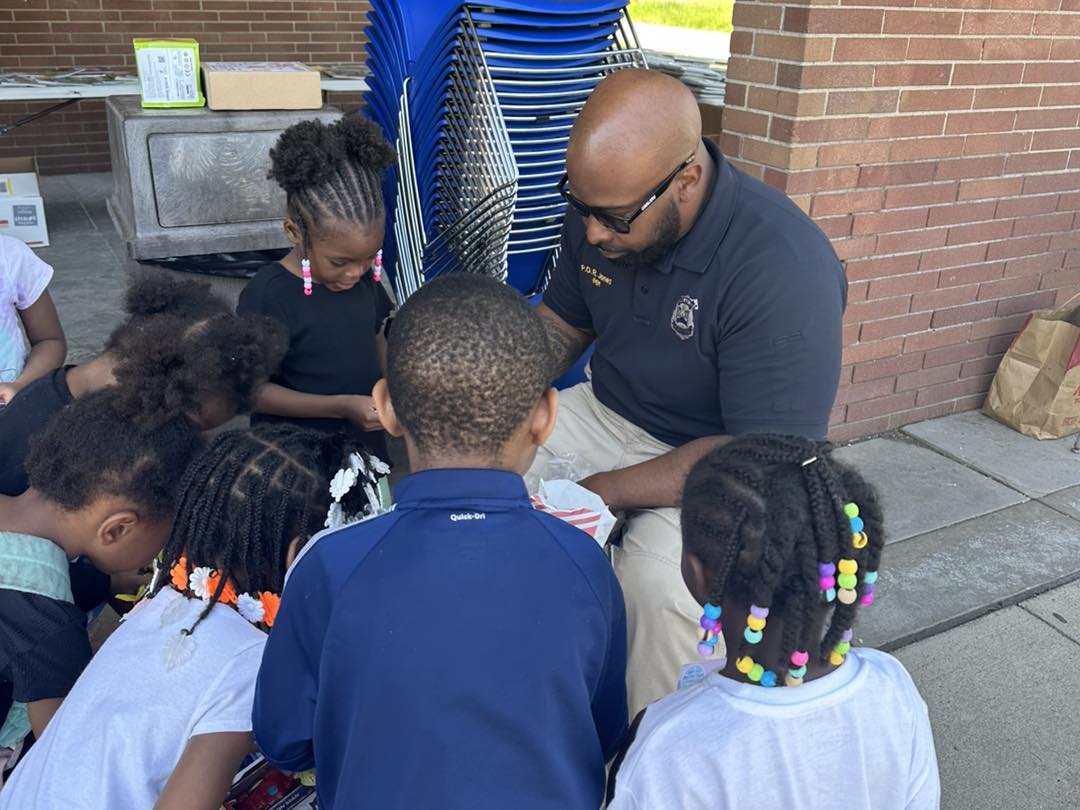 Officer kneeling and engaging with a group of young children