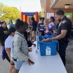 Officer handing out toys to a student while others wait in line