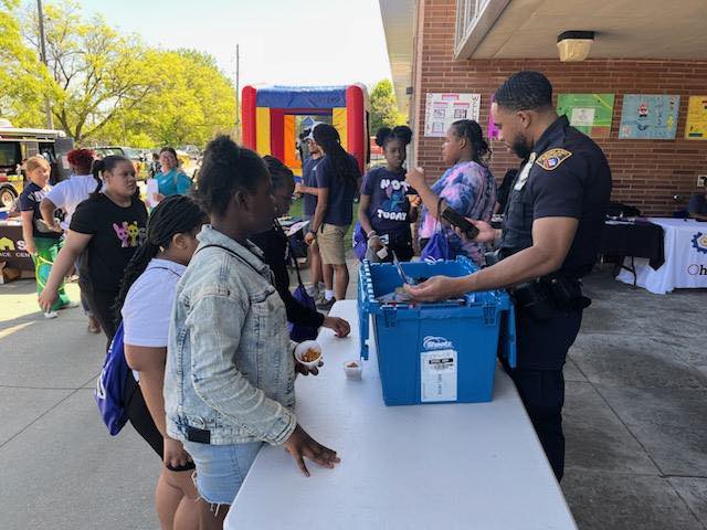 Officer handing out toys to a student while others wait in line