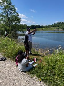 Children and adults fish along the lakeshore on a bright summer day at the Cops for Kids event.