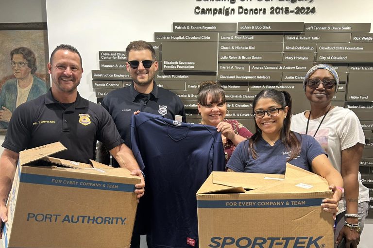 Officers and May Dugan Center staff pose with donated clothing boxes from Sports Focus