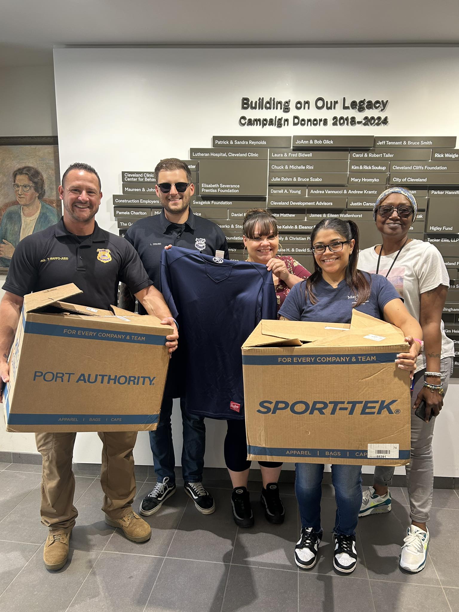 District 2 Dugan Center Clothing Drop-Off Officers and May Dugan Center staff pose with donated clothing boxes from Sports Focus