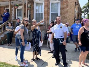 Commander Maffo-Judd and Councilwoman Santana listen to a resident pointing out concerns during the neighborhood walkthrough, as neighbors and officers gather nearby.