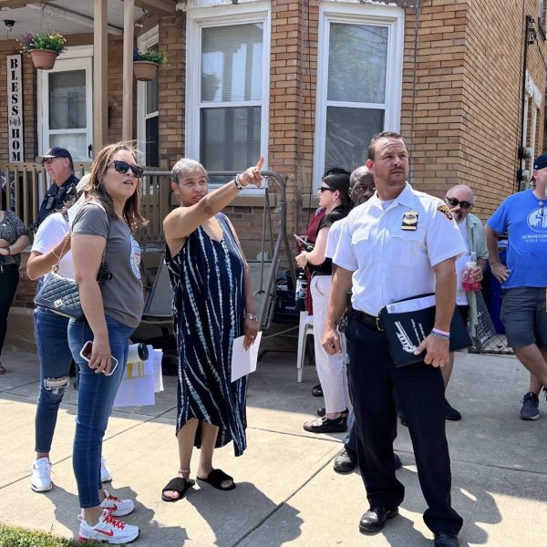 Commander Maffo-Judd and Councilwoman Santana listen to a resident pointing out concerns during the neighborhood walkthrough, as neighbors and officers gather nearby.