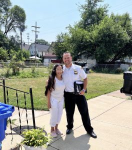 Commander Maffo-Judd poses arm-in-arm with a smiling resident in her yard.