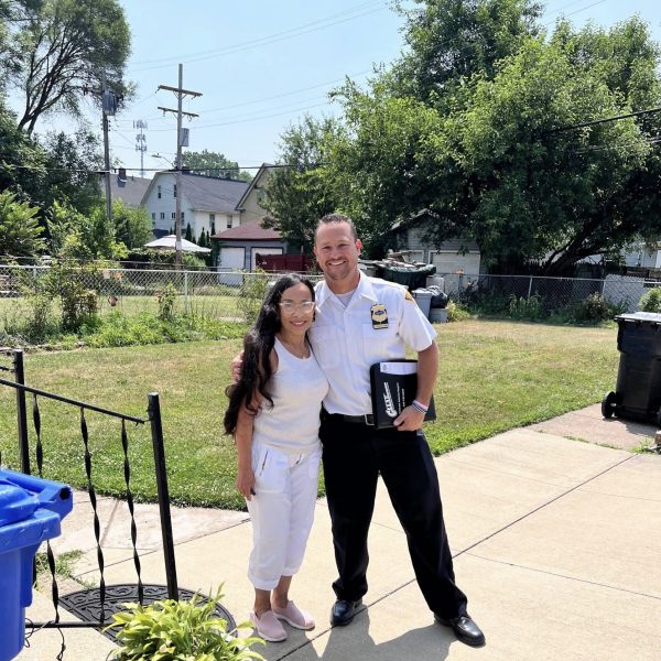 Commander Maffo-Judd poses arm-in-arm with a smiling resident in her yard.