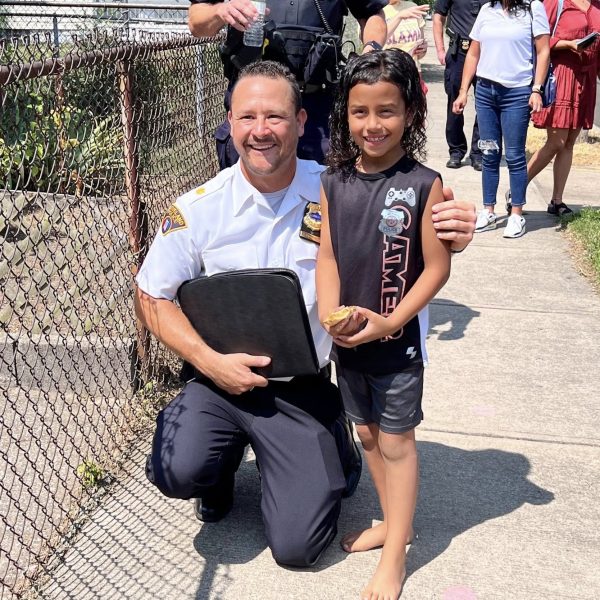 Commander Maffo-Judd kneels beside a smiling child during the walk