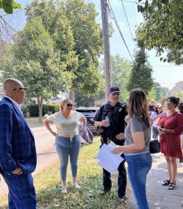 Councilwoman Santana speaks with officers and residents on a tree-lined street