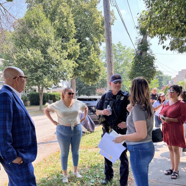 Councilwoman Santana speaks with officers and residents on a tree-lined street