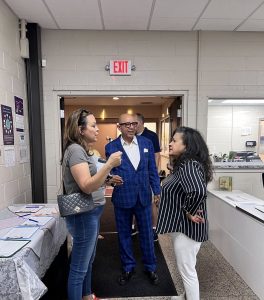 Councilwoman Santana, a sharply dressed man in blue plaid, and another woman speak in the entryway of a local building during the safety walk’s indoor kickoff.