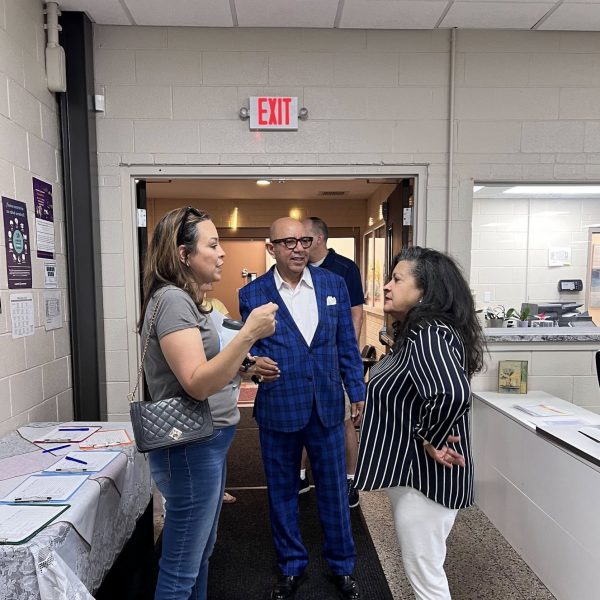 Councilwoman Santana, a sharply dressed man in blue plaid, and another woman speak in the entryway of a local building during the safety walk’s indoor kickoff.