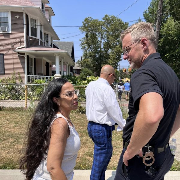 Sergeant Thomas and a community member chat casually on the sidewalk, with other participants visible in the background.