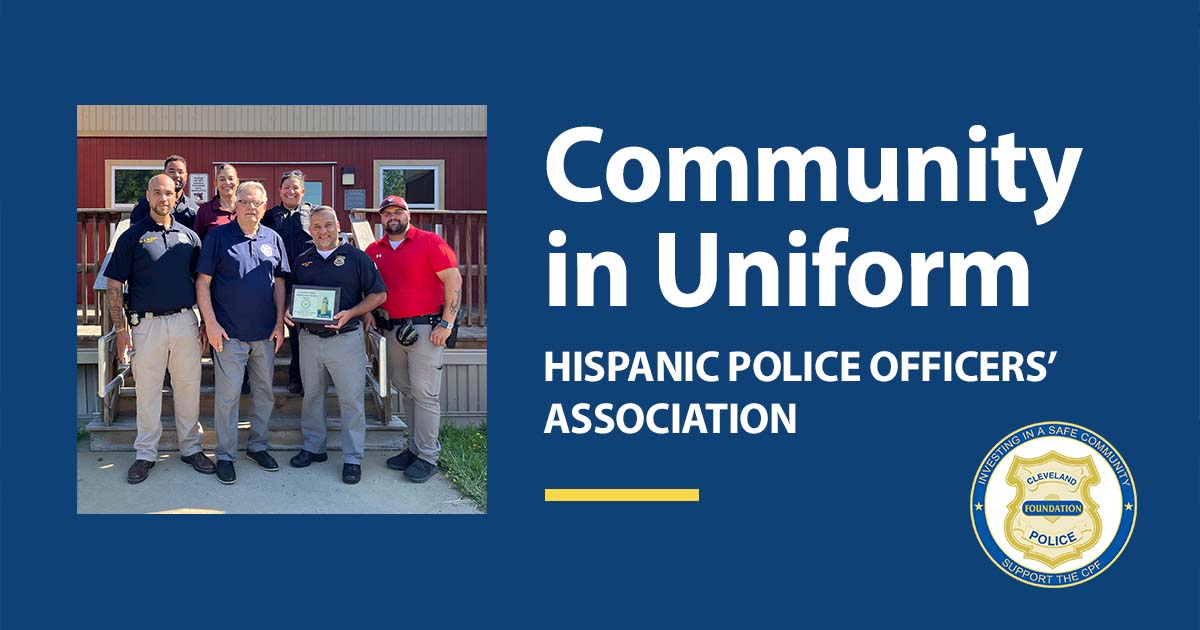 Members of the Hispanic Police Officers’ Association pose with a Cleveland Police Foundation plaque outside a red building.