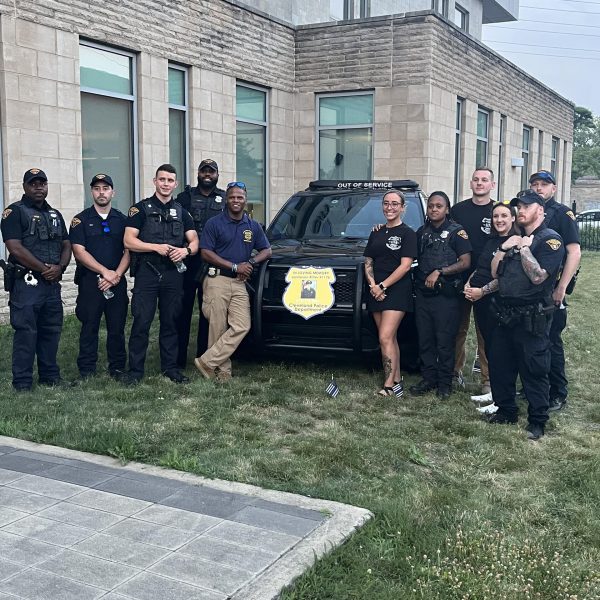 Officers stand together beside the memorial-marked patrol vehicle outside the 3rd District.