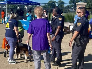 Officers chat with senior walkers and a dog near the Cleveland Water outreach booth and other event tables.