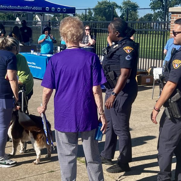 Officers chat with senior walkers and a dog near the Cleveland Water outreach booth and other event tables.