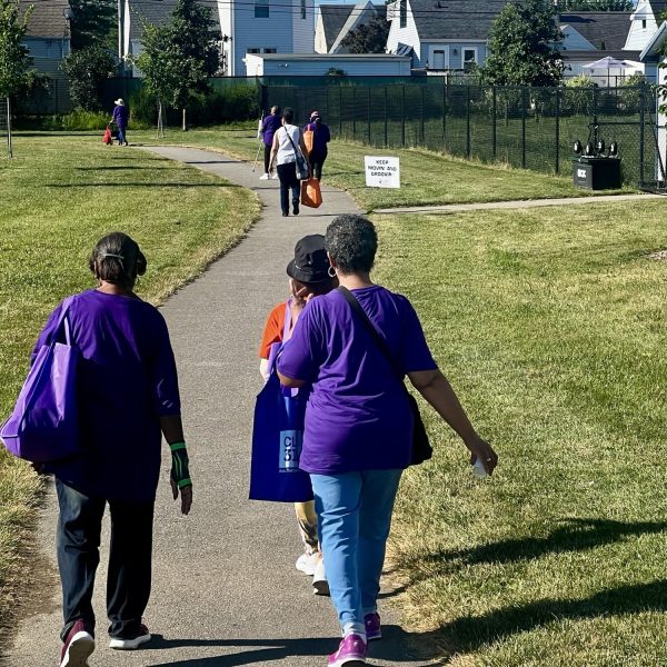 Seniors walk the park path in small groups carrying giveaway bags during the Cleveland Senior Walk event.