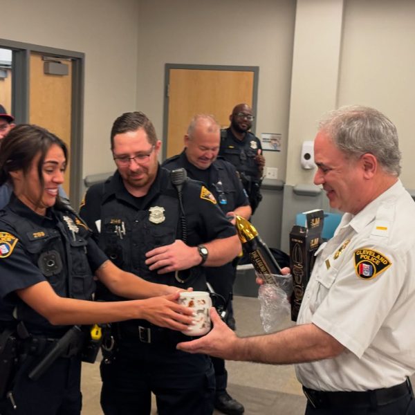 Lt. Sanders receives parting gifts and a mug from fellow officers, smiling during the celebration