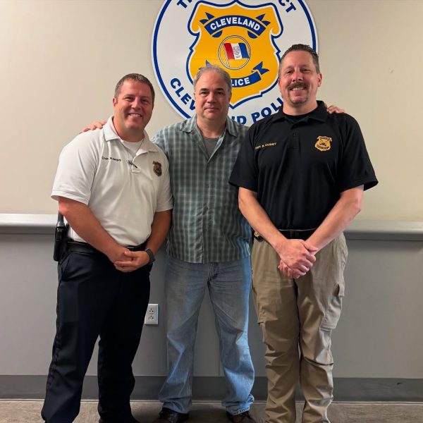 Lt. Sanders poses with Commander Maguschak and another officer in front of the Third District seal