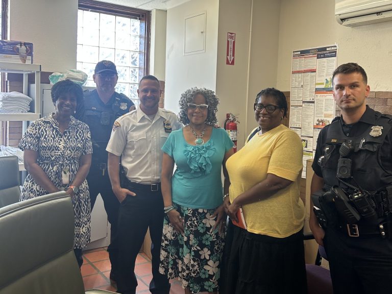 Second District officers and YWCA staff pose together inside a women’s facility during a safety and community partnership visit.