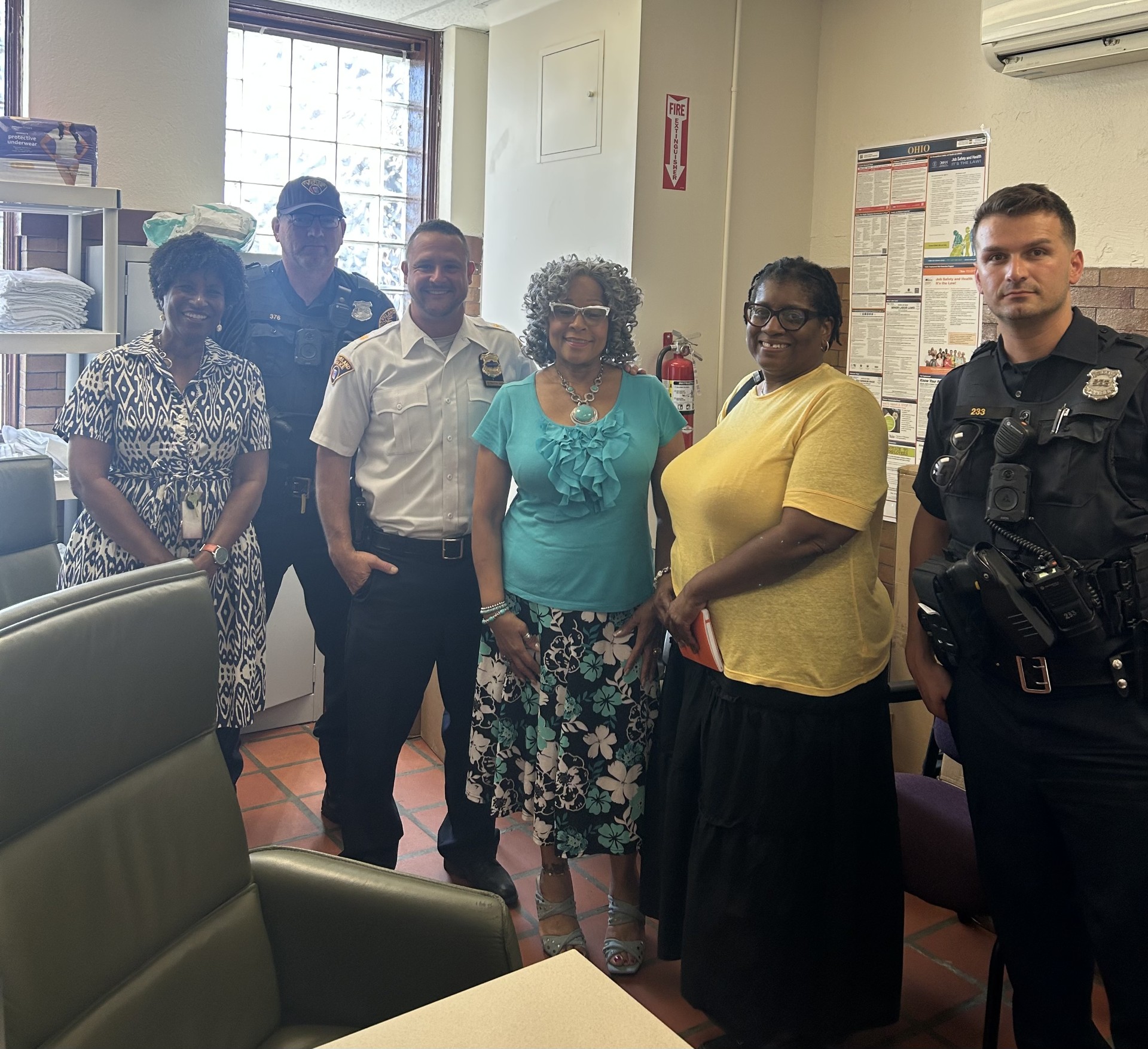 Second District officers and YWCA staff pose together inside a women’s facility during a safety and community partnership visit.