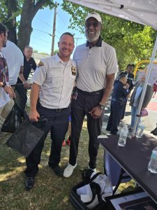 A Cleveland officer stands with a guest under a tent at the event, with others gathered in the background near the court.